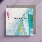 "Engaged" square greeting card with a turquoise and gold alcohol ink design and a grey envelope