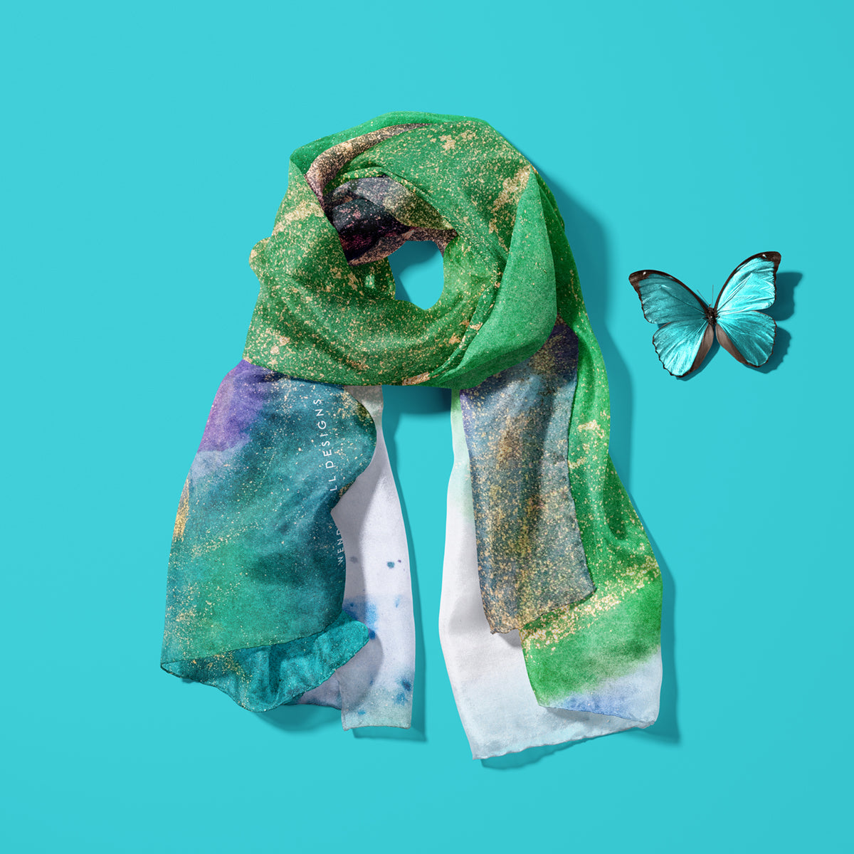 Green and gold coloured, luxurious British silk scarf on a turquoise background