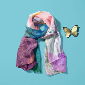 Light and soft, feminine silk scarf with a pretty pattern laid on a blue background with a yellow butterfly next to it