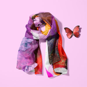 Fiery orange and purple, light silk twill scarf laid on a pink background with a red butterfly next to it